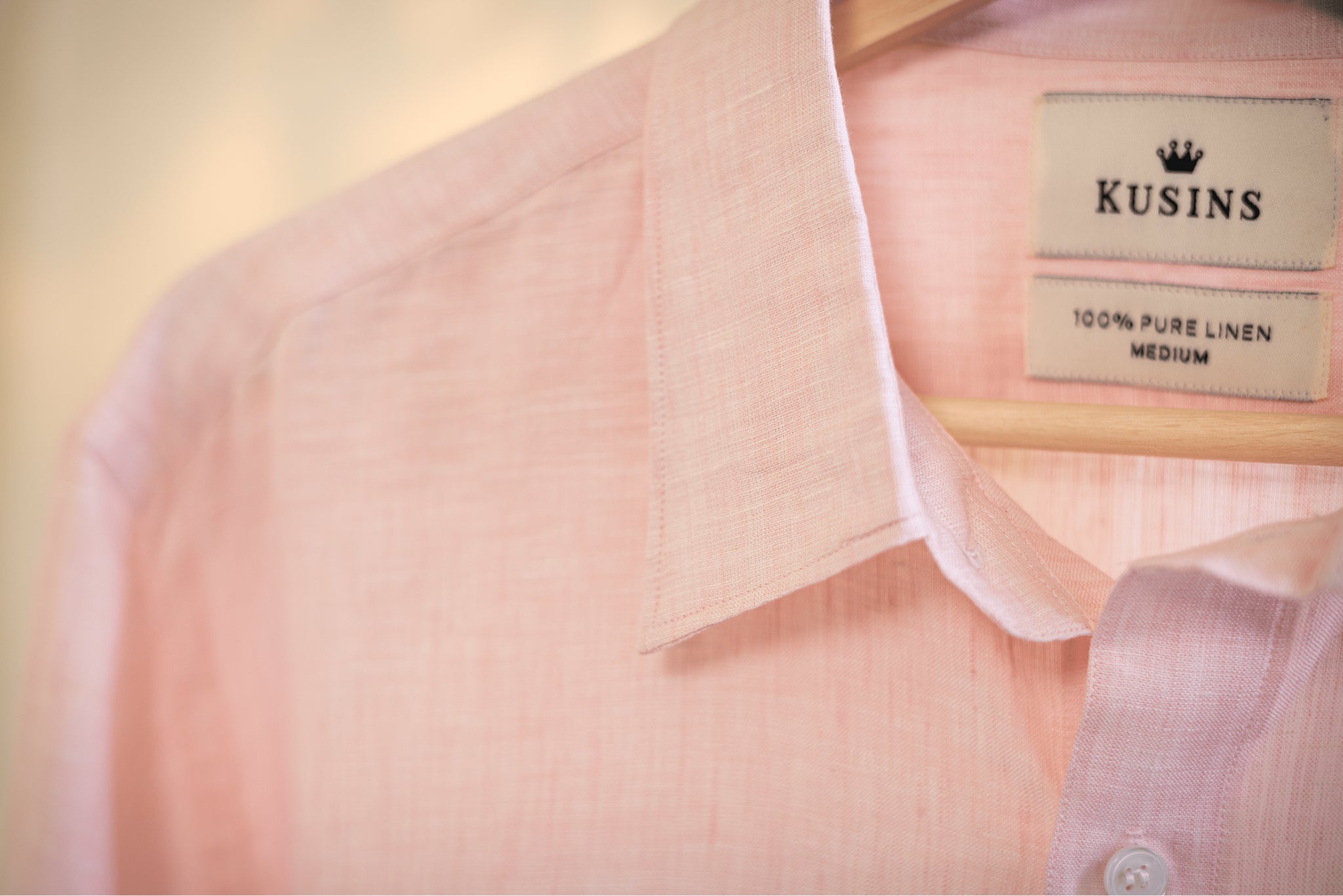 Close-up of a Blush / pink shirt with a Kusins label on a blurred background