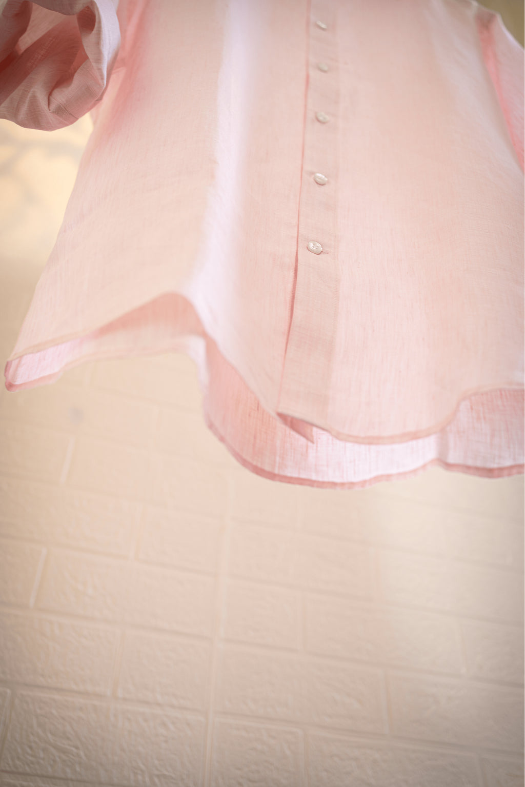 Close-up of a Blush / light pink blouse with a textured background