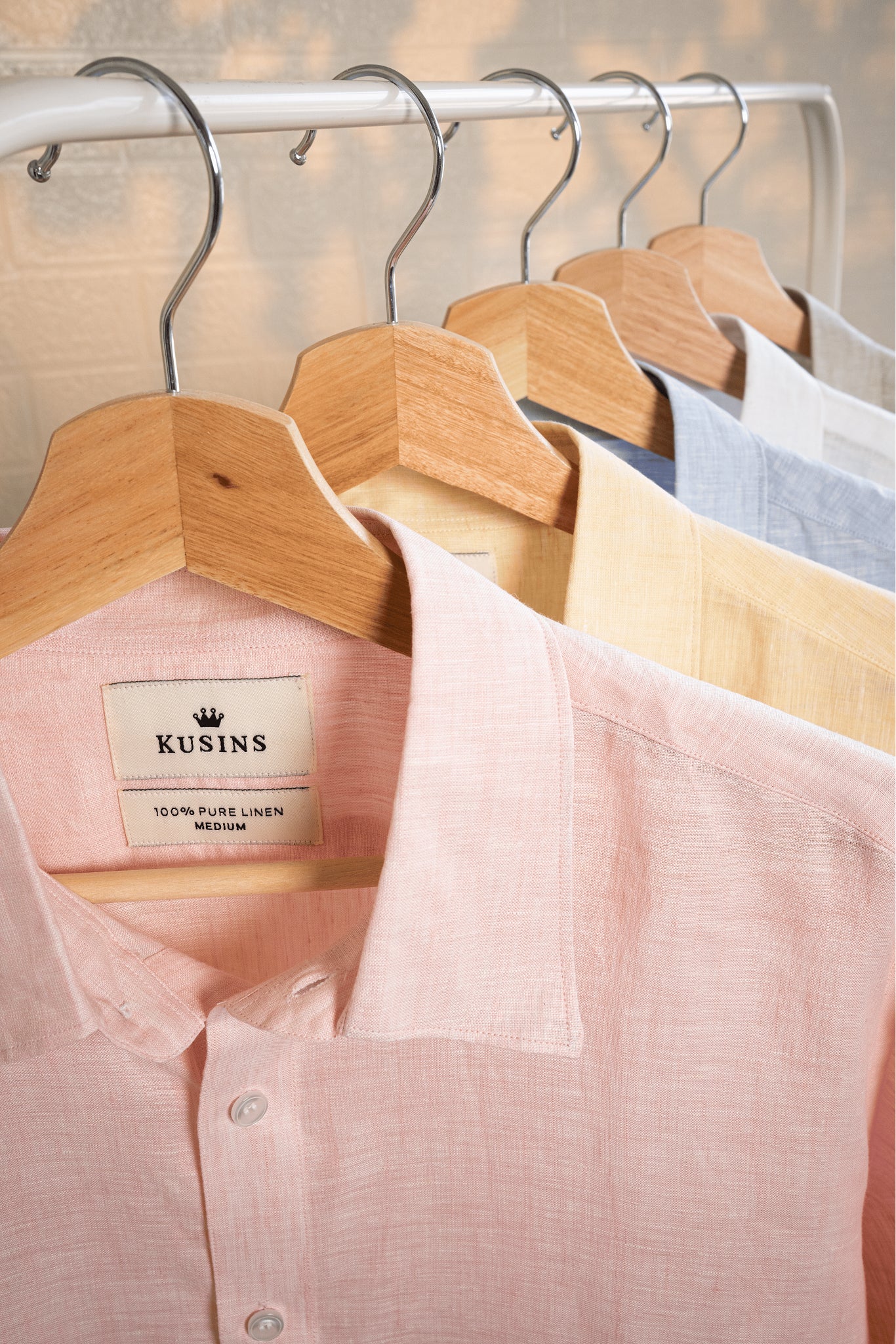 Blush / pink linen shirt on hangers with other shirts in the background