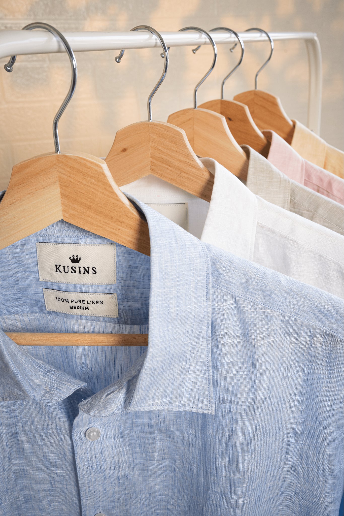 Ocean / Blue shirt on a wooden hanger with 'Kusins' label, surrounded by other shirts.