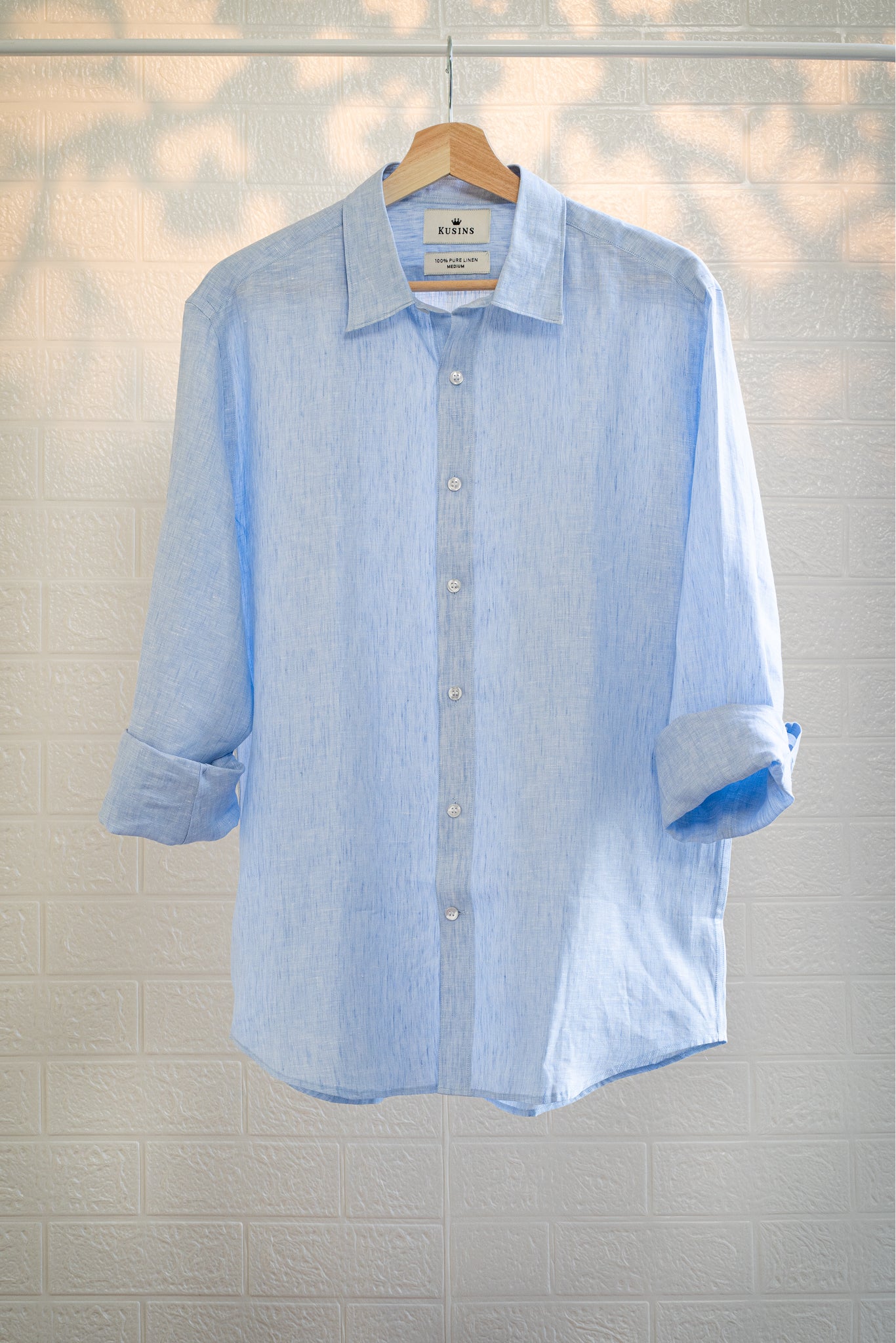 Ocean / Light blue striped shirt on a hanger against a light tiled wall.