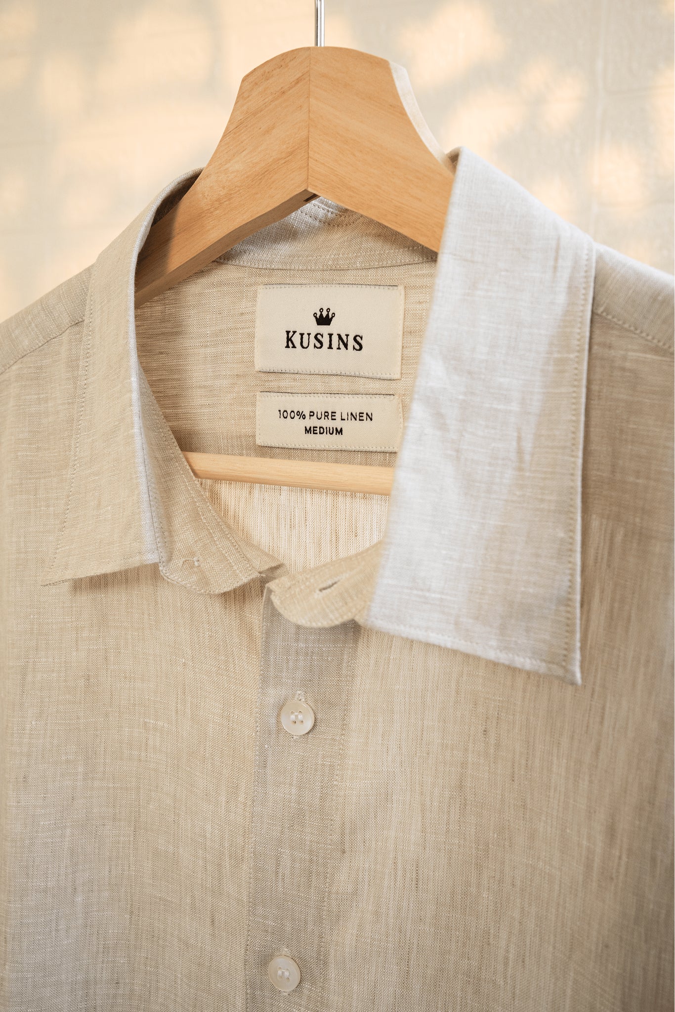 Sand / Beige linen shirt on a hanger with 'Kusins' label
