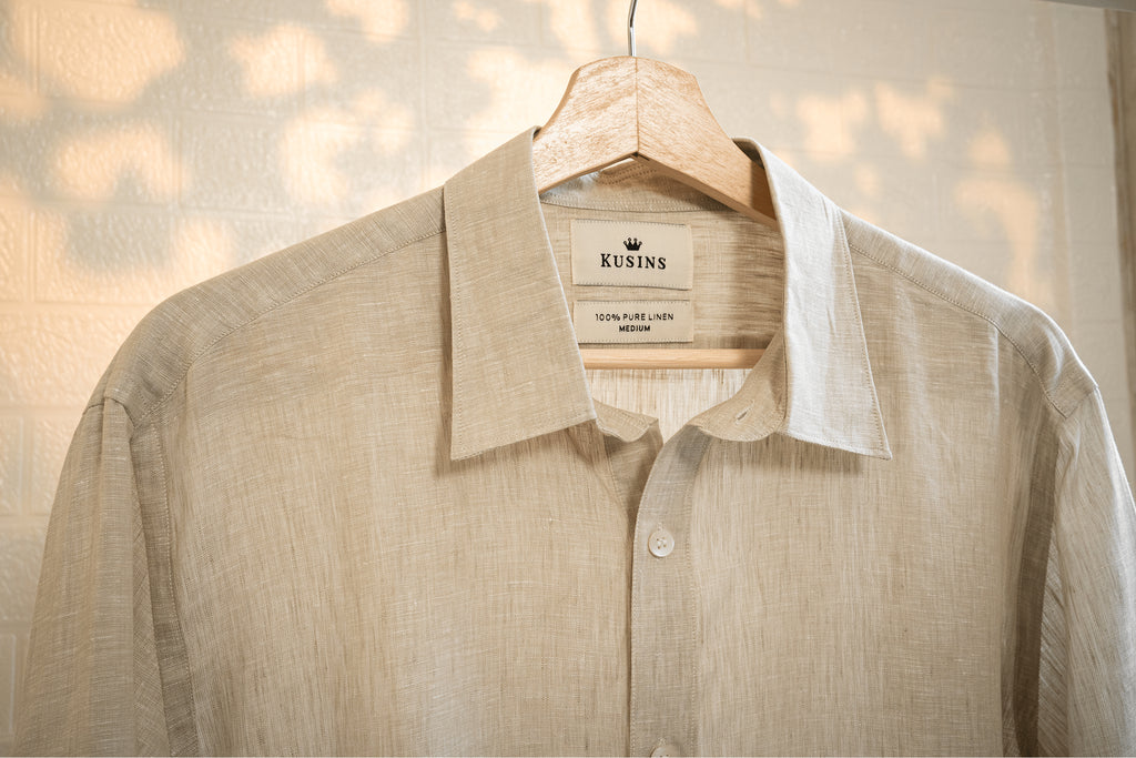Sand / Beige shirt on a hanger with 'Kusins' label against a blurred background