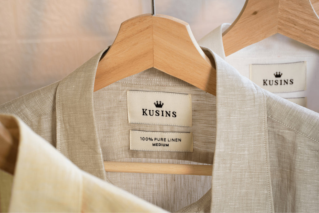 Sand / beige  linen shirt on a hanger with 'Kusins' branding.