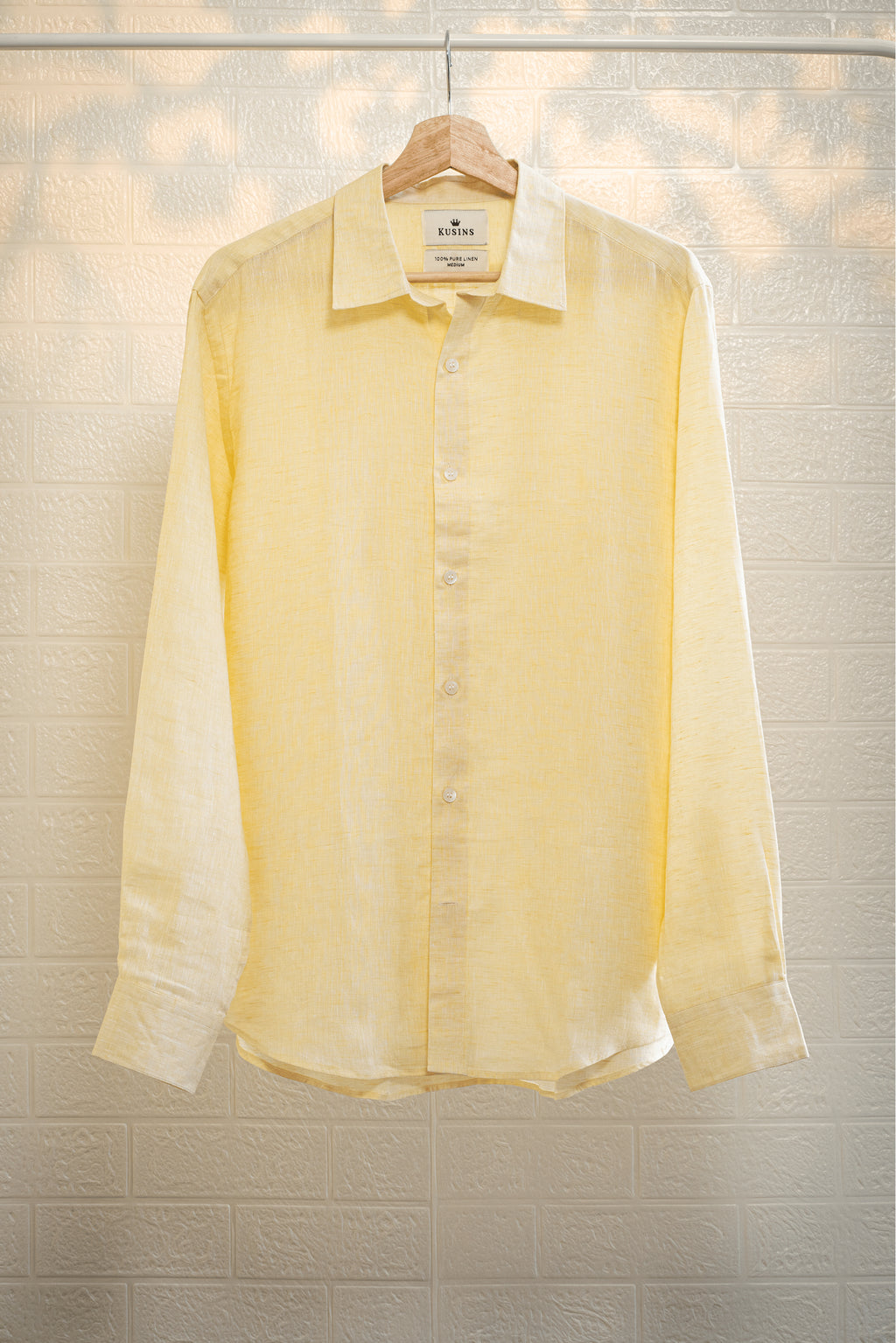 Summer / Yellow shirt on a hanger against a textured wall background