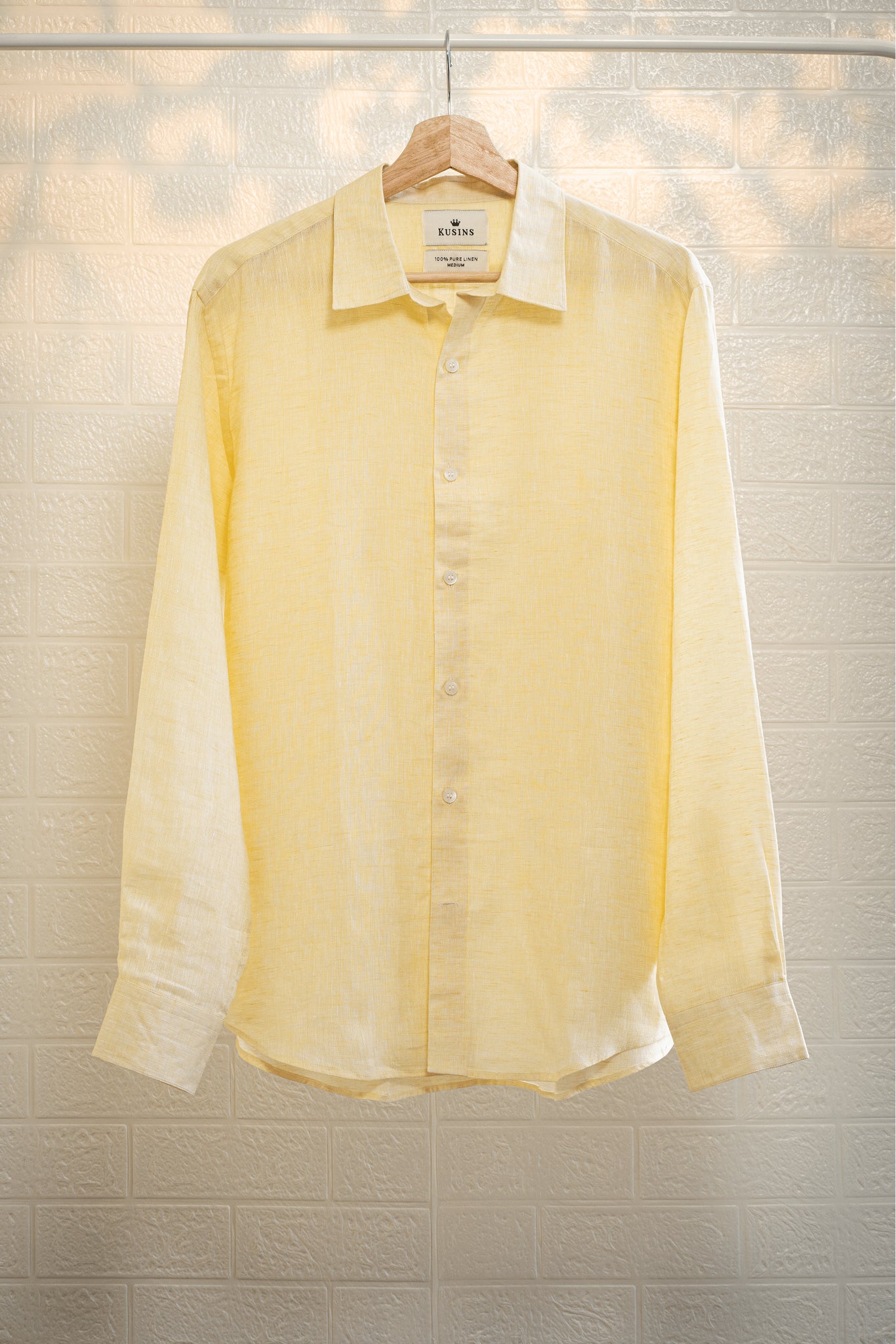 Summer / Yellow shirt on a hanger against a textured wall background