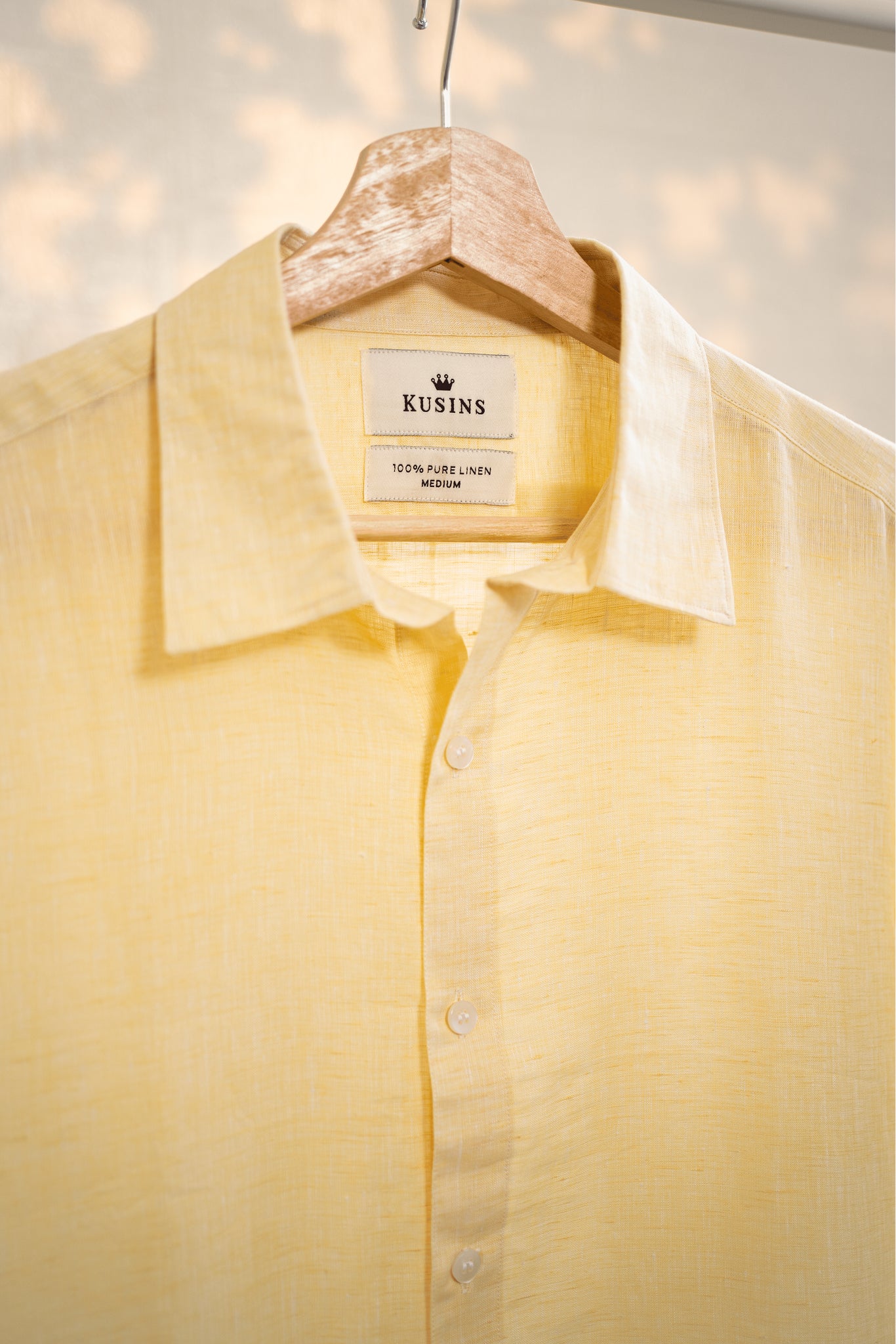 Summer / Yellow shirt on a hanger with 'Kusins' label against a light background