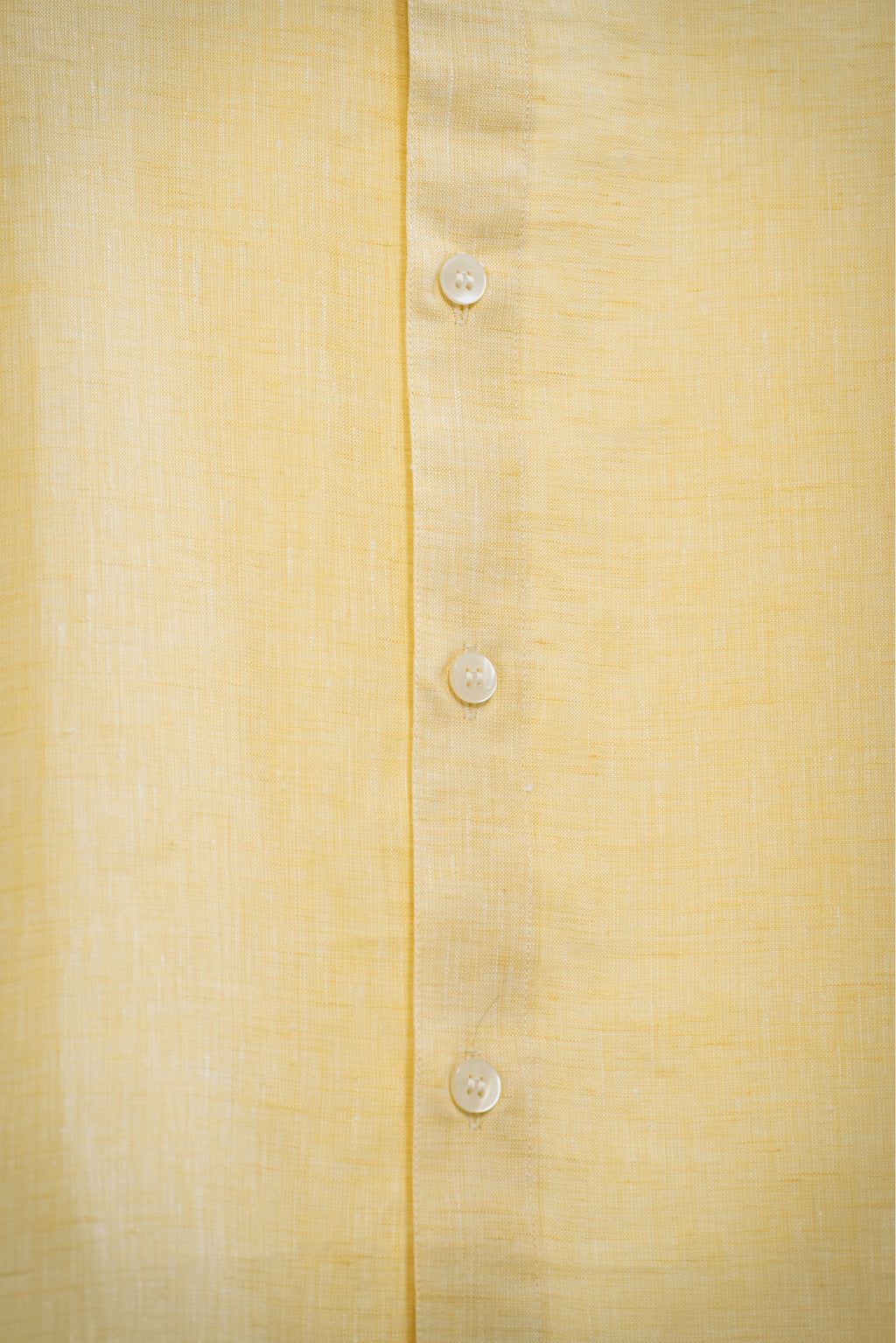 Close-up of a Summer  / yellow shirt with buttons on a textured fabric background