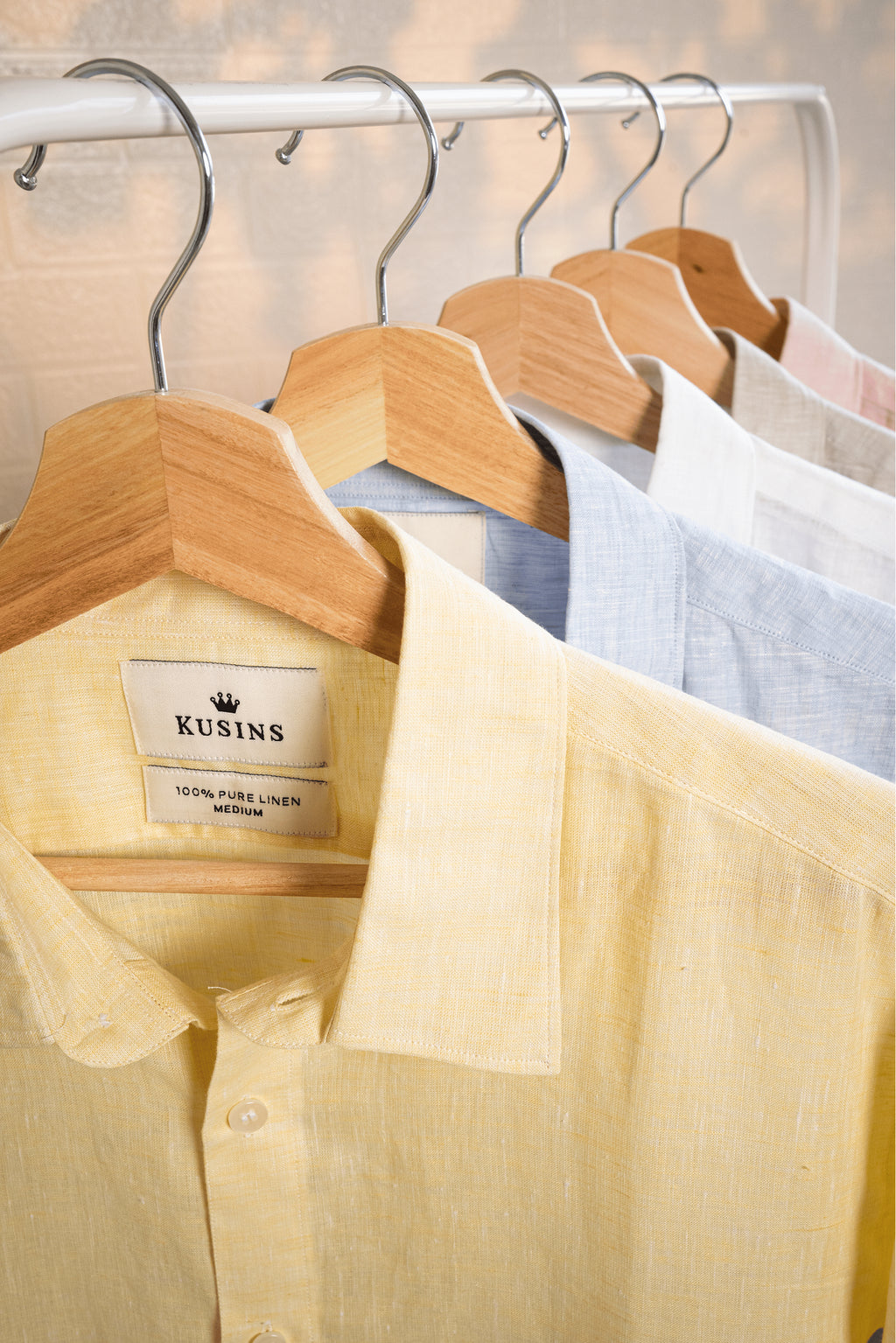 Summer  /  Yellow shirt on a hanger with a visible brand label against a neutral background
