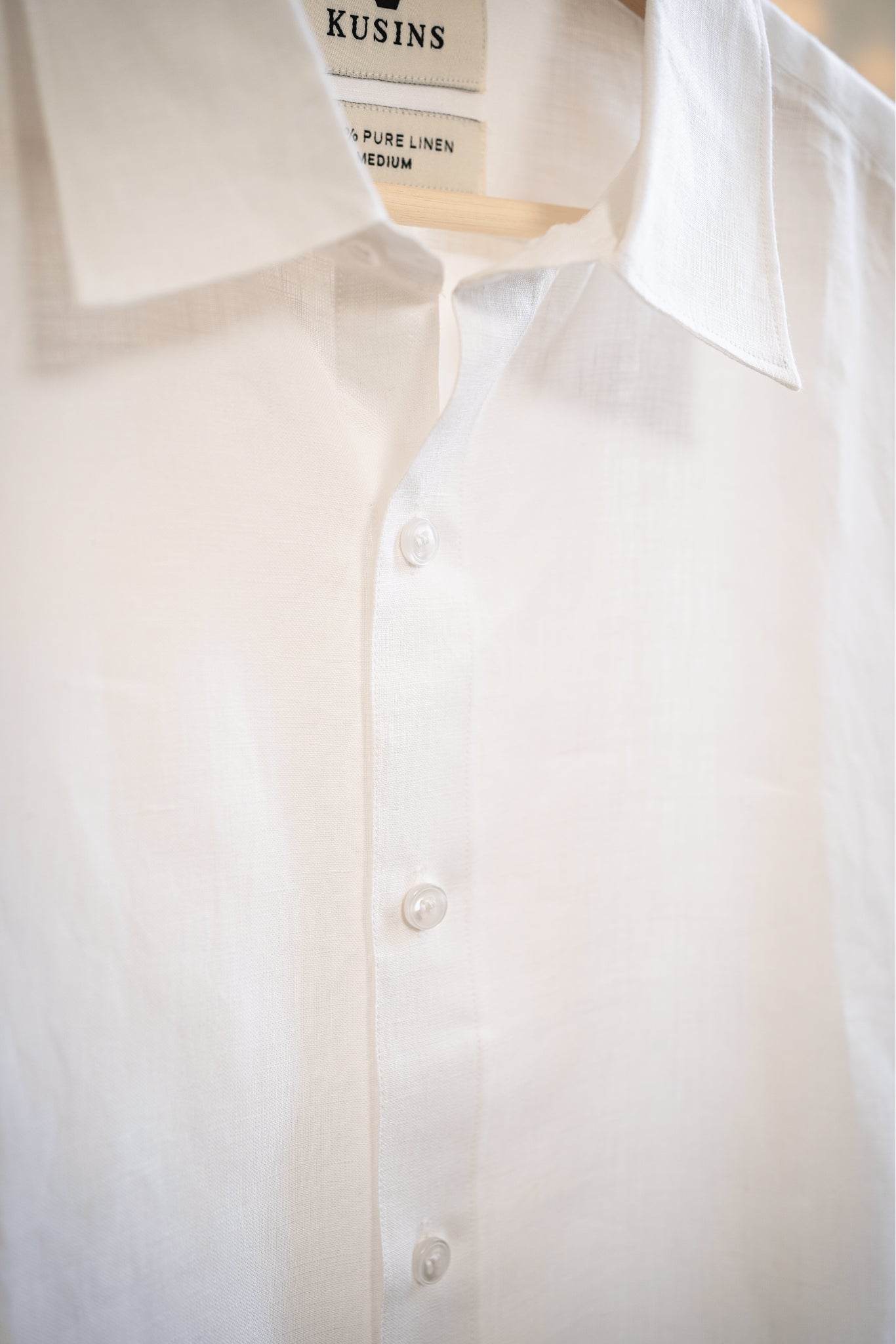 Close-up of a chalk or white shirt with visible branding on buttons